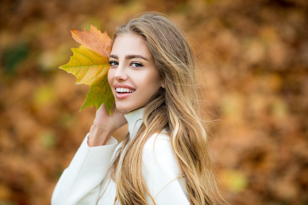 가을을 들고 귀여운 미소 여자는 자연 야외에서 leafs. 근심 걱정 없는 행복.