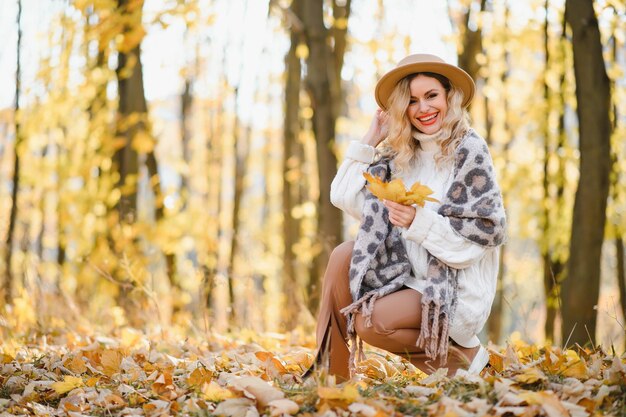 Photo cute smiley woman holding autumn leafs in the nature.