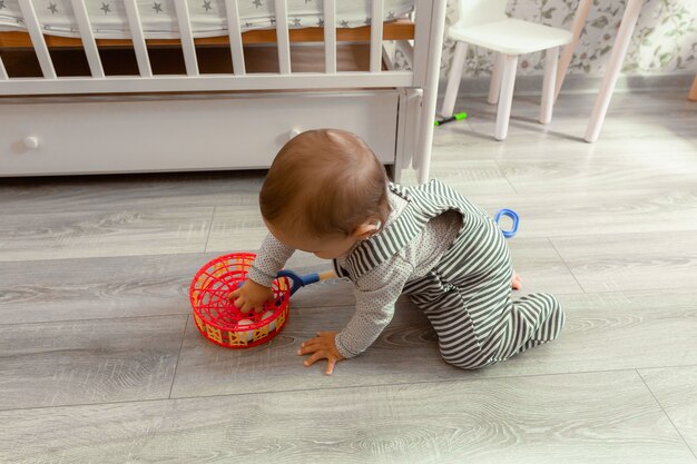 写真 生後12ヶ月のかわいい笑顔の赤ちゃんが自分の部屋の床に座っておもちゃで遊んでいます。