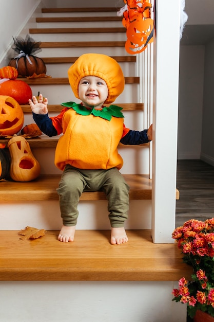 Bambino sorridente sveglio vestito da zucca che guarda l'obbiettivo