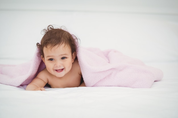 Cute smiling baby lying under blanket 