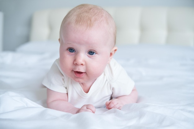 写真 親のベッドでおなかの上に横たわるかわいい笑顔の赤ちゃん