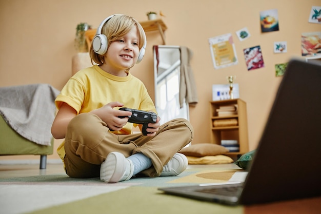 Cute smiling boy in headphones pressing gamepad buttons