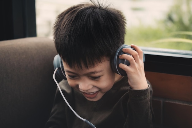 cute smiling boy listening music on headphones at home