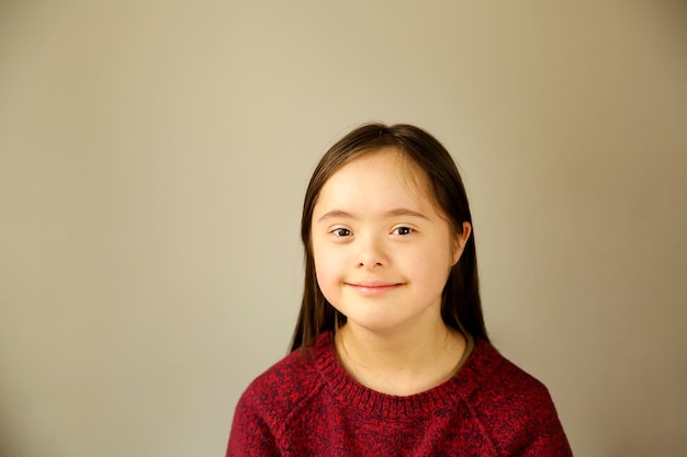 Cute smiling down syndrome girl on the brown background