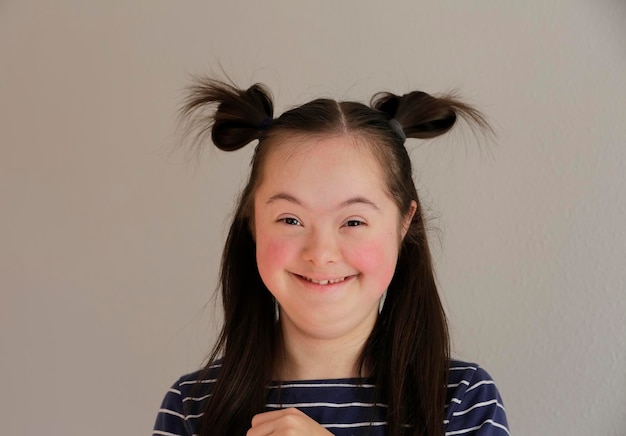 Cute smiling down syndrome girl on the grey background