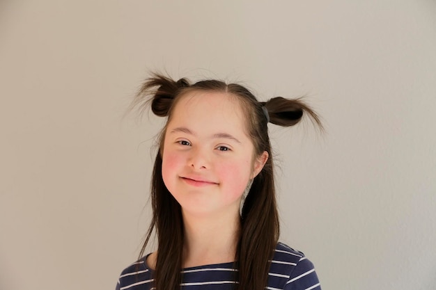 Cute smiling down syndrome girl on the grey background