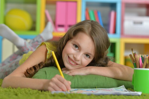 Cute smiling girl drawing at home