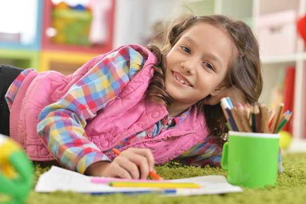 cute smiling girl lying on floor and drawing at home