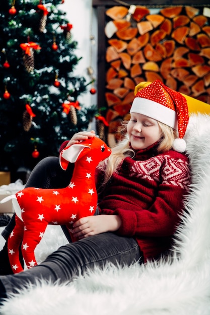 Cute smiling girl playing with toy while sitting on fur during christmas