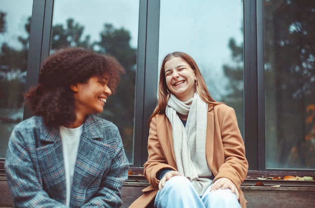 Photo cute smiling girls sitting against glass outdoors