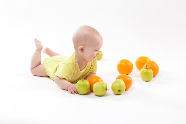 Cute smiling healthy child lies among frui