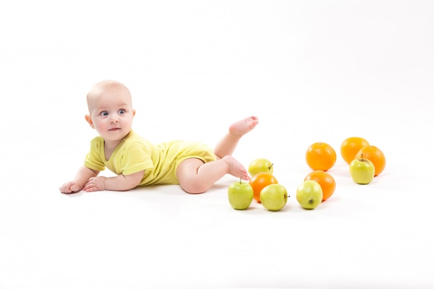 Cute smiling healthy child lies among fruits