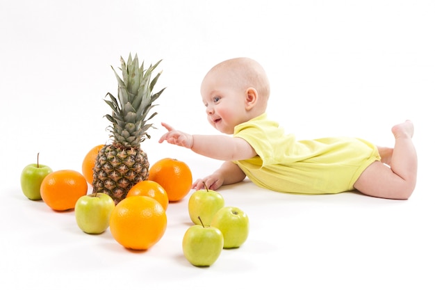 cute smiling healthy child lies on a white background among frui