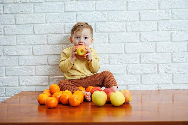 신선한 육즙이 많은 빨간 사과 하나를 먹는 귀여운 웃는 아이 어린 아이들을 위한 건강한 과일