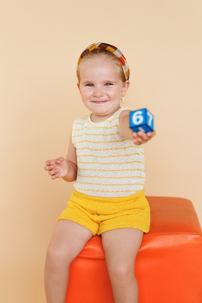 Cute smiling little girl on an orange chair