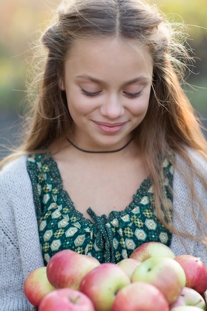 Cute smiling little girl with a basket of apples on a farm