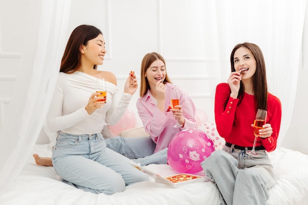 Cute smiling multiracial women enjoying wine tasting chocolate sweets celebrating birthday