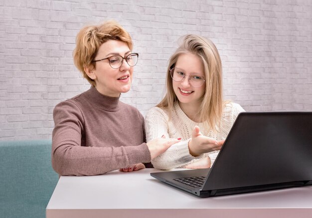 Foto ragazza teenager e madre sorridenti sveglie che utilizzano il computer portatile in casa. madre e figlia a casa. adolescente.