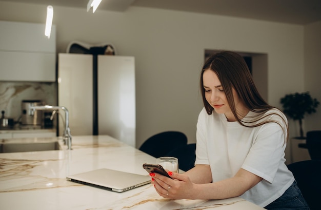 Cute smiling woman reading or searching recipe Student girl using smartphone at home Connection communication online shopping distance learning studying lockdown concept