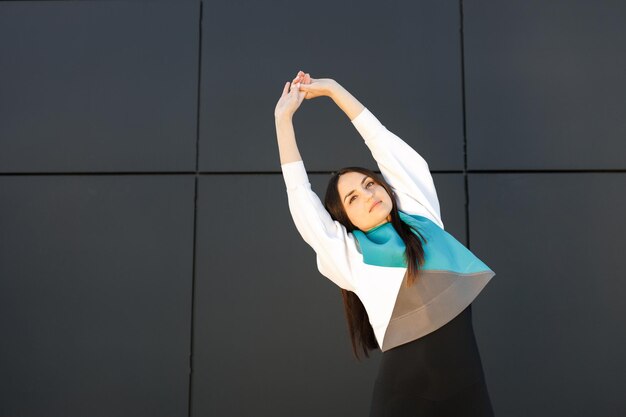 Cute sporty girl doing stretching on the street before training