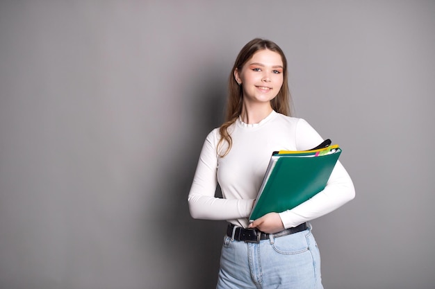 A cute student girl holds notebooks for notes and smiles