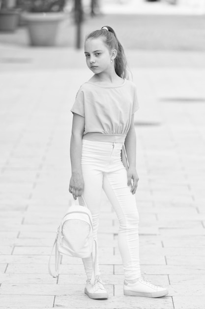 Cute and stylish Adorable girl of fashion on summer day Fashionable girl child on city street Small girl with beauty look Little girl with long blond hair in casual fashion style