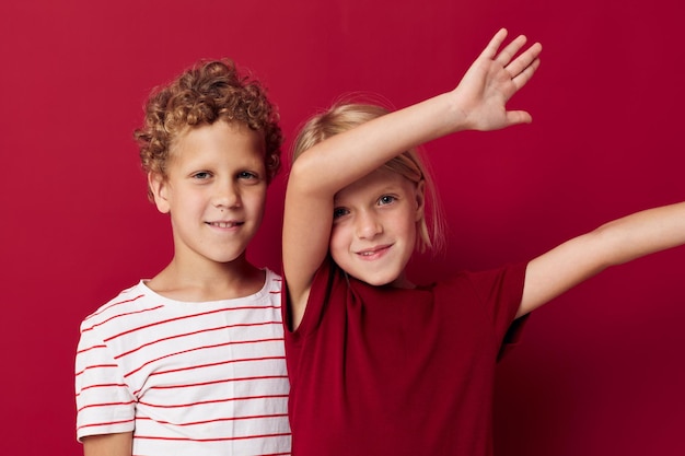 Симпатичные стильные дети веселятся детскими развлечениями на красном фоне