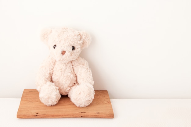 Cute teddy bear seat on wood 