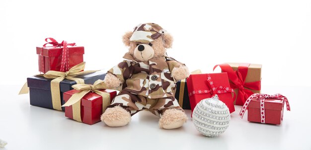 Cute teddy bear in soldier uniform and xmas presents isolated against white background