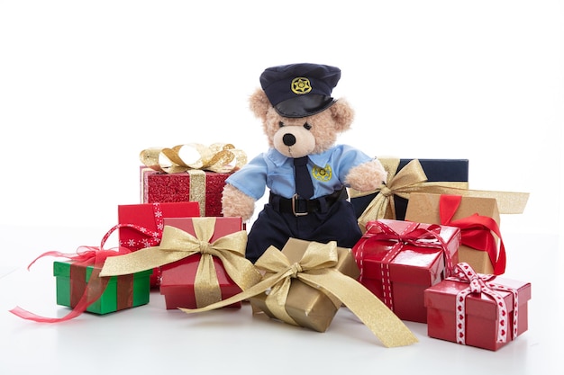 Cute teddy in policeman uniform and christmas presents isolated against white background