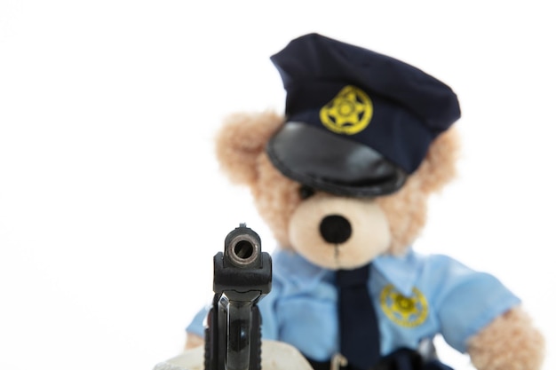 Cute teddy in policeman uniform holding gun isolated against white background