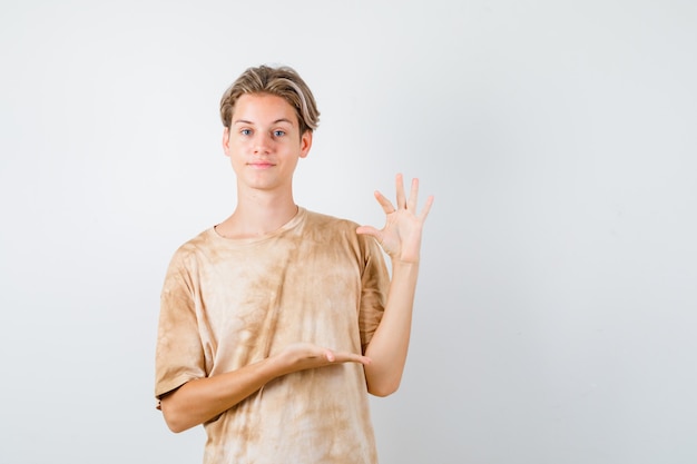 Cute teen boy showing small size sign in t-shirt and looking confident , front view.