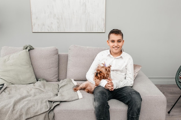 Cute teen boy sitting together with a dog on the couch