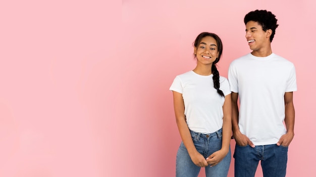 Cute teen couple posing on pink background with free space