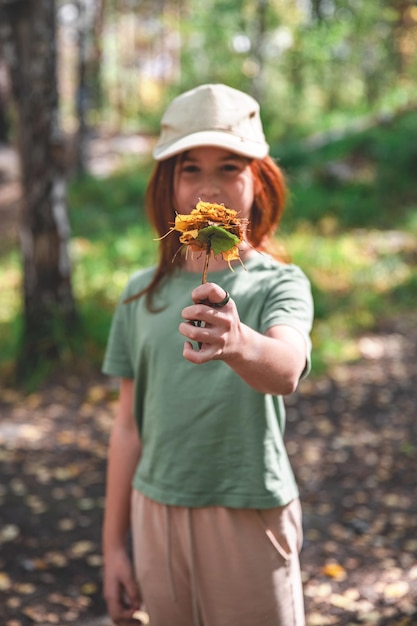 Photo cute teen girl holding autumn yellow leaves on a shelf in front of her