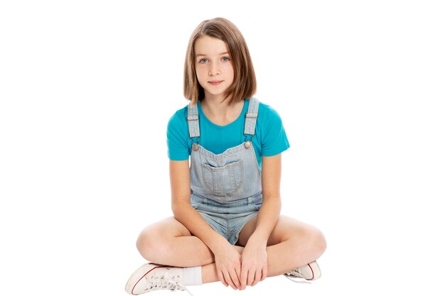 Cute teen girl sitting. Isolated on a white background.