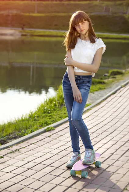 Cute teen girl on a skateboard on the street.