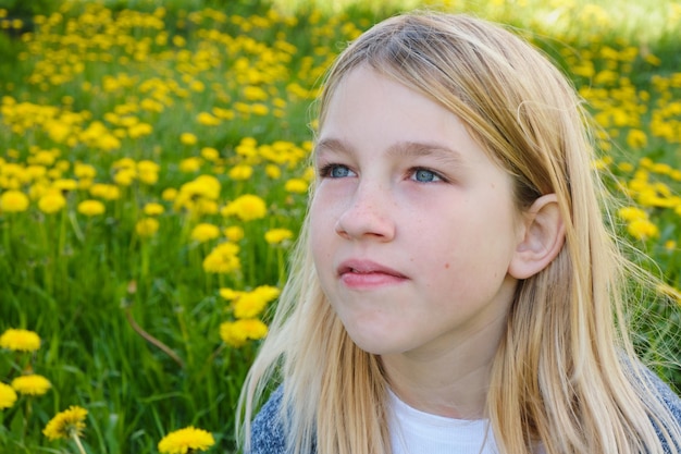 Cute teen girl in a summer field with dandelions