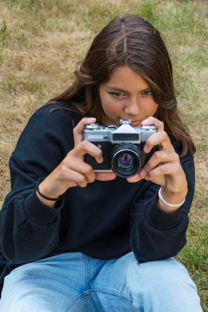 Foto ragazza teenager sveglia con una macchina fotografica una ragazza che scatta foto su una macchina fotografica d'annata retrò sull'erba