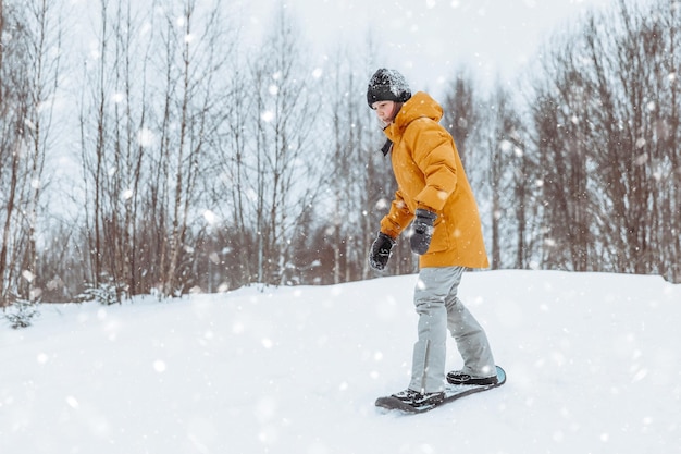 Cute teenage girl rides a snowskate in a winter park healthy lifestyle