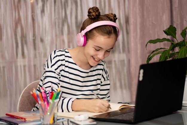 家庭の学校技術教育から勉強しているかわいい10代の少女