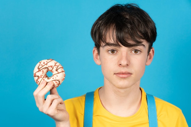 Cute teenager boy holding sweet chocolate cupcake on hand