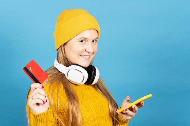 Cute teenager girl holding credit card and phone