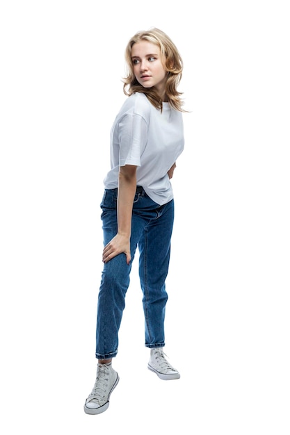 A cute teenager girl in jeans and a white Tshirt is standing Full height Isolated on white background Vertical