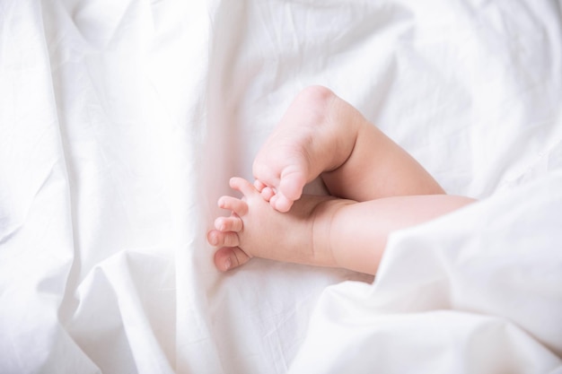 ベッドの上の女の赤ちゃんのかわいい小さな足