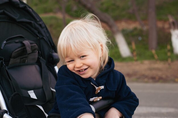 Cute toddler baby boy in a baby stroller
