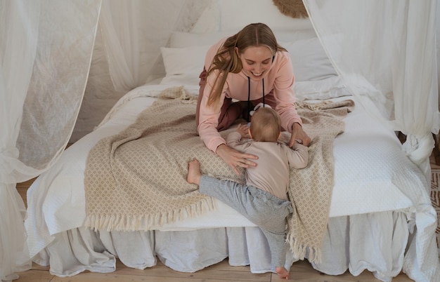 Photo cute toddler baby climbing on bed happy family at home care support first step concept