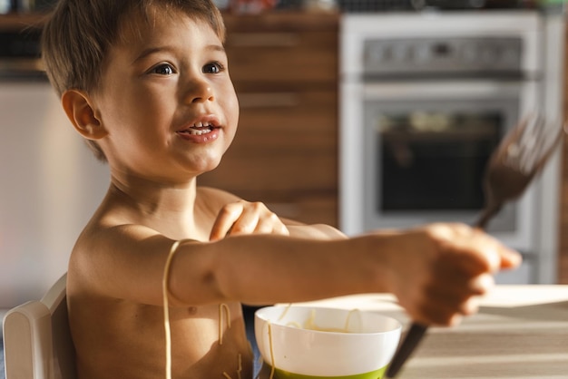 Cute toddler boy eating his favorite food Spaghetti