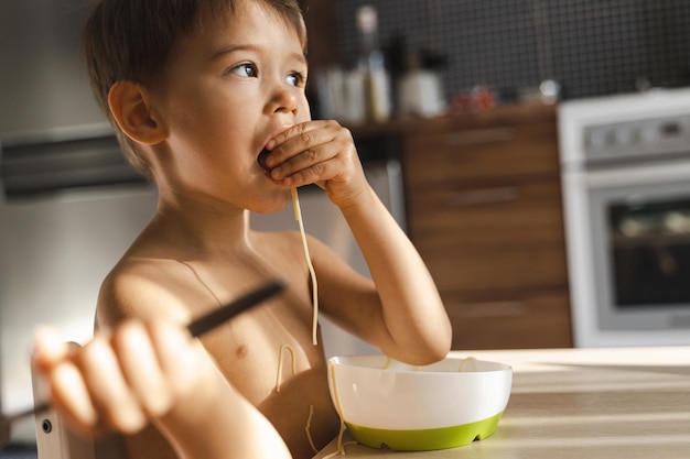 Cute toddler boy eating his favorite food Spaghetti